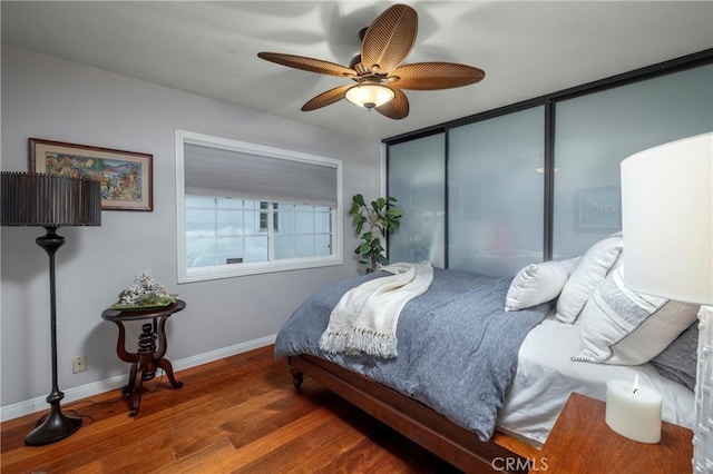 bedroom featuring wood finished floors, baseboards, a closet, and a ceiling fan