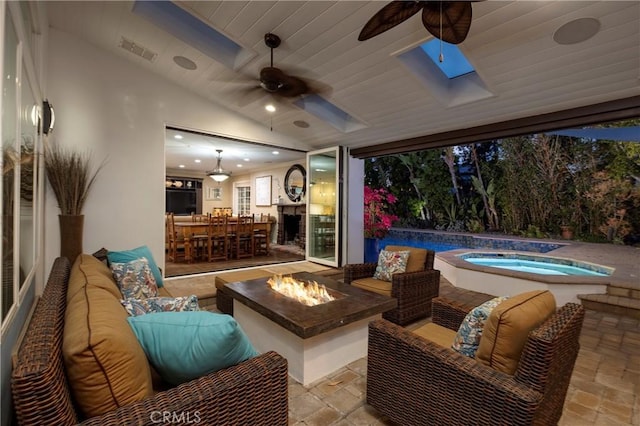 view of patio featuring a ceiling fan, an in-ground hot tub, and an outdoor living space with a fire pit