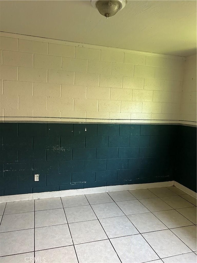 empty room featuring concrete block wall and tile patterned floors