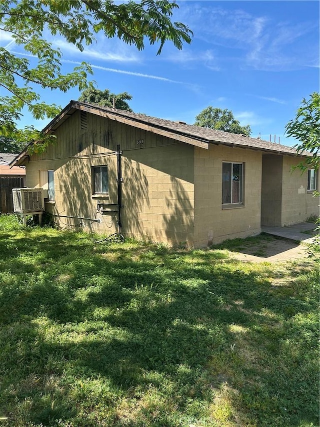 view of side of property with concrete block siding and a yard