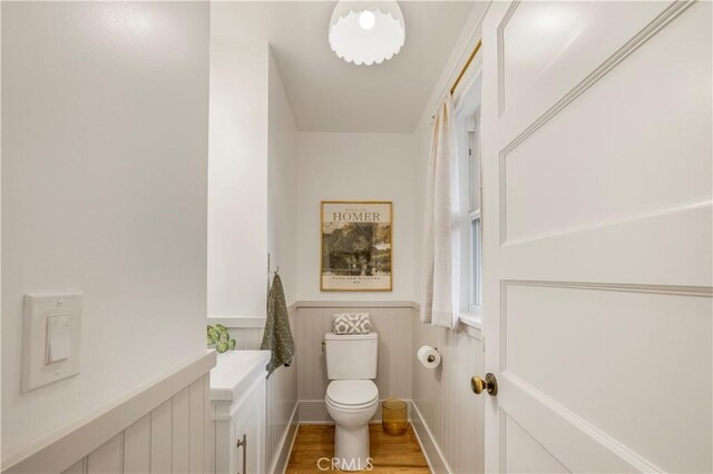 bathroom featuring toilet, a wainscoted wall, and wood finished floors