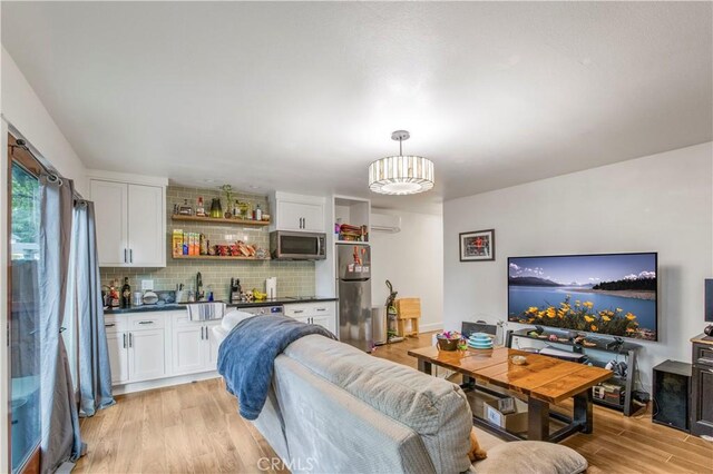 living room featuring wet bar, light wood-style flooring, a wall mounted air conditioner, and a chandelier