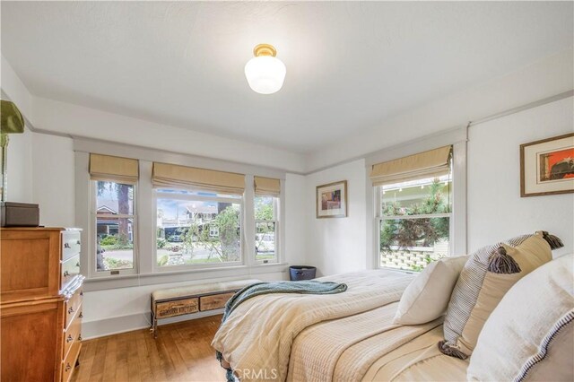 bedroom with multiple windows and light wood-style flooring