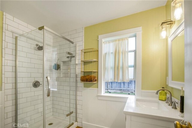 full bath with a shower stall, wainscoting, and vanity