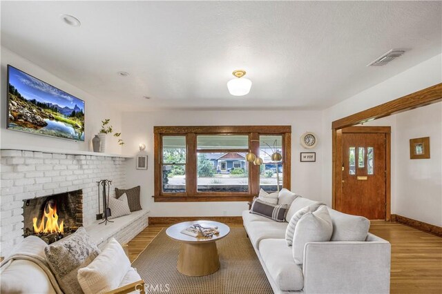 living room featuring healthy amount of natural light, wood finished floors, a fireplace, and baseboards