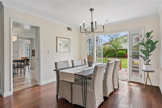 dining area with a chandelier, dark wood-type flooring, crown molding, and baseboards