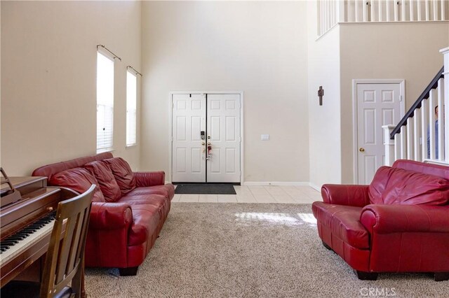 carpeted living room featuring a high ceiling, tile patterned flooring, stairway, and baseboards