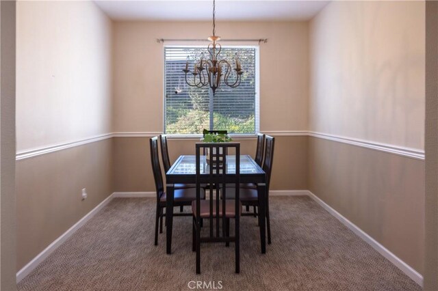 dining room with a chandelier, carpet flooring, and baseboards