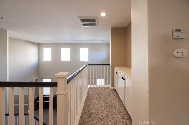 hall featuring carpet floors and an upstairs landing