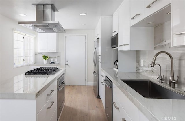 33156 Ocean Bright, Dana Point, CA 92629 - kitchen with island exhaust hood, a sink, appliances with stainless steel finishes, white cabinetry, and light wood finished floors