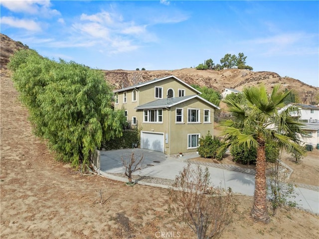 28637 Chiquito Canyon Rd, Castaic, CA 91384 - rear view of property with concrete driveway, a mountain view, an attached garage, and stucco siding