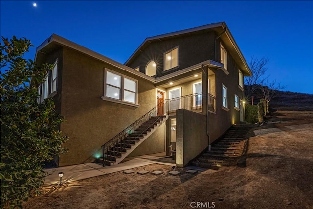 28637 Chiquito Canyon Rd, Castaic, CA 91384 - back of house at night featuring stairs, stucco siding, and a patio area