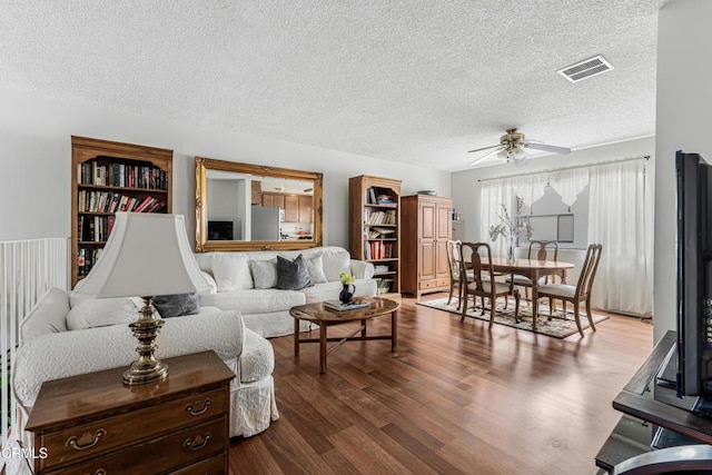 living area with a textured ceiling, a ceiling fan, and dark wood-style flooring