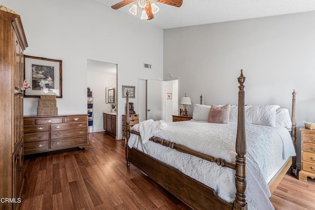 bedroom with dark wood-style floors, high vaulted ceiling, ensuite bathroom, a ceiling fan, and baseboards