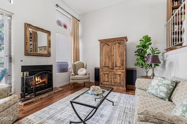 living room with healthy amount of natural light, a warm lit fireplace, and wood finished floors