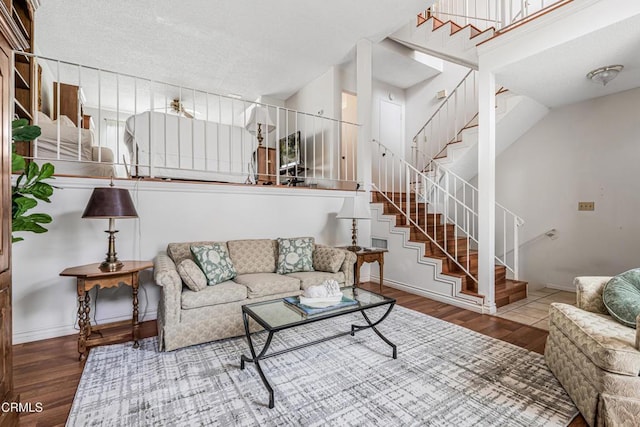 living area featuring wood finished floors, baseboards, and stairway
