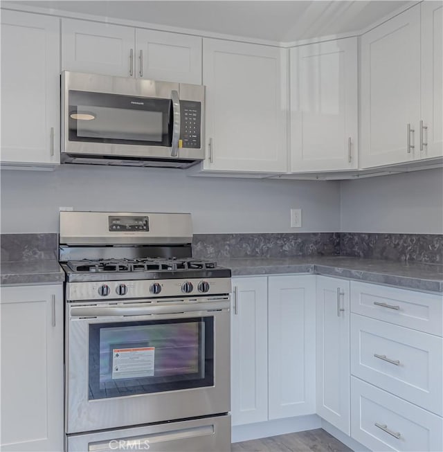2726 W Orion Ave, Santa Ana, CA 92704 - kitchen featuring appliances with stainless steel finishes, white cabinetry, dark countertops, and light wood-style floors
