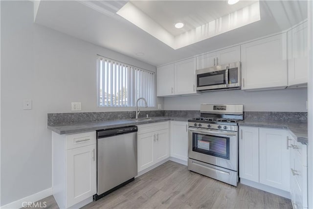 2726 W Orion Ave, Santa Ana, CA 92704 - kitchen with appliances with stainless steel finishes, white cabinets, light wood finished floors, dark countertops, and recessed lighting