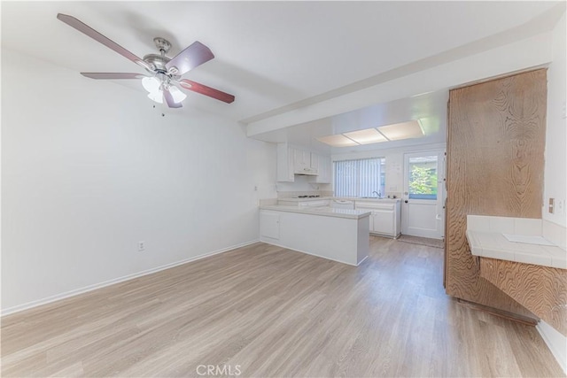2726 W Orion Ave, Santa Ana, CA 92704 - kitchen featuring a peninsula, light countertops, light wood-type flooring, and white cabinetry