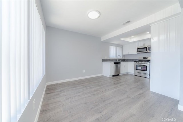 2726 W Orion Ave, Santa Ana, CA 92704 - kitchen with appliances with stainless steel finishes, white cabinets, light wood-type flooring, and a tray ceiling