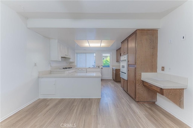 2726 W Orion Ave, Santa Ana, CA 92704 - kitchen featuring light wood-type flooring, a warming drawer, oven, light countertops, and a peninsula