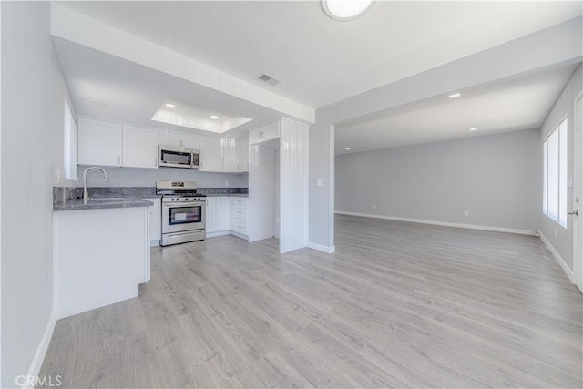 2726 W Orion Ave, Santa Ana, CA 92704 - kitchen with appliances with stainless steel finishes, recessed lighting, white cabinetry, light wood-type flooring, and a tray ceiling