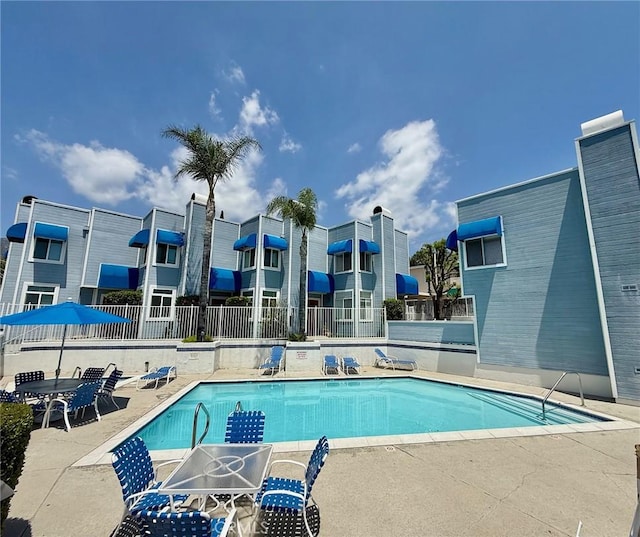 community pool with fence and a patio area