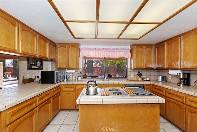 20407 Eyota Ln, Apple Valley, CA 92308 - kitchen featuring light tile patterned floors, decorative backsplash, stainless steel microwave, stovetop with downdraft, and a kitchen island