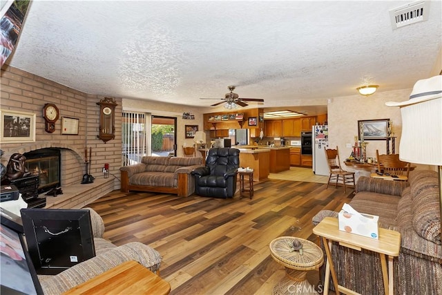 20407 Eyota Ln, Apple Valley, CA 92308 - living area with a textured ceiling, a fireplace, light wood-style floors, and ceiling fan