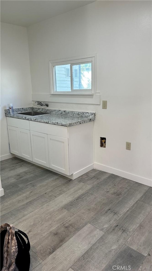 interior space featuring a sink, wood finished floors, and baseboards