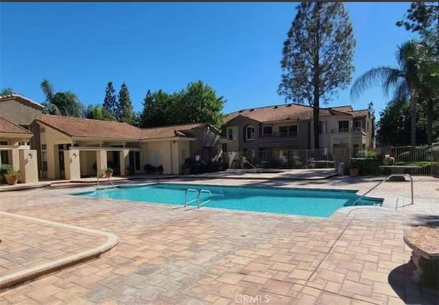 community pool with a patio and fence