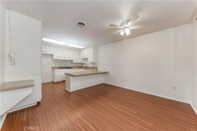 2619 W Aurora St, Santa Ana, CA 92704 - kitchen with a peninsula, gas cooktop, a ceiling fan, wood finished floors, and white cabinets