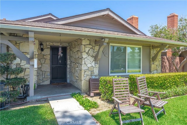 2619 W Aurora St, Santa Ana, CA 92704 - doorway to property with stone siding, a chimney, a porch, and a shingled roof