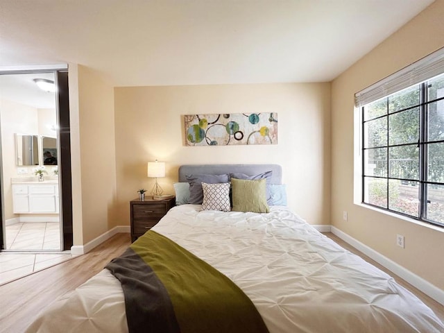 13272 Wimberly Sq Unit 219, San Diego, CA 92128 - bedroom with baseboards, light wood-type flooring, and ensuite bathroom
