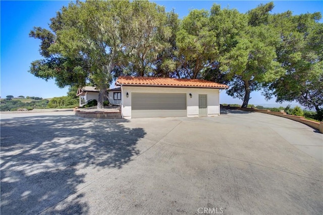 view of front of property with stucco siding, a tiled roof, driveway, and a garage