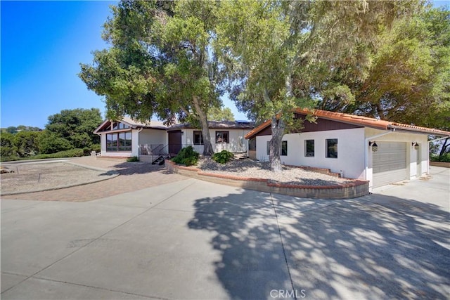 ranch-style house with concrete driveway, an attached garage, and stucco siding