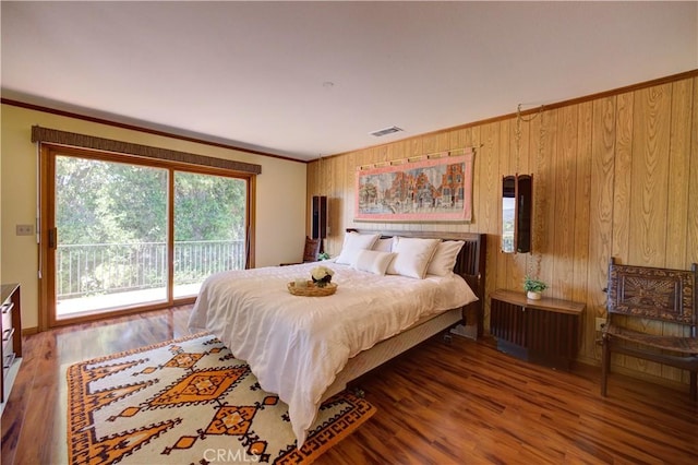 bedroom featuring access to exterior, wood walls, crown molding, and wood finished floors