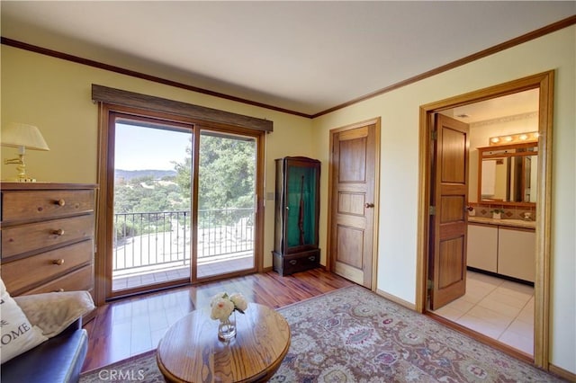 living area with crown molding, light wood-style floors, and baseboards