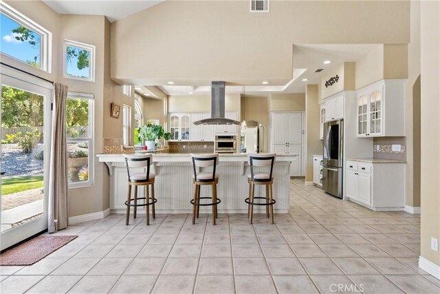 11620 Cenegal Rd, Atascadero, CA 93422 - kitchen featuring island range hood, appliances with stainless steel finishes, a peninsula, glass insert cabinets, and a kitchen breakfast bar