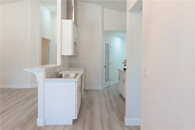 16241 Chestnut St, Hesperia, CA 92345 - kitchen featuring a sink, white cabinetry, light wood finished floors, and light countertops