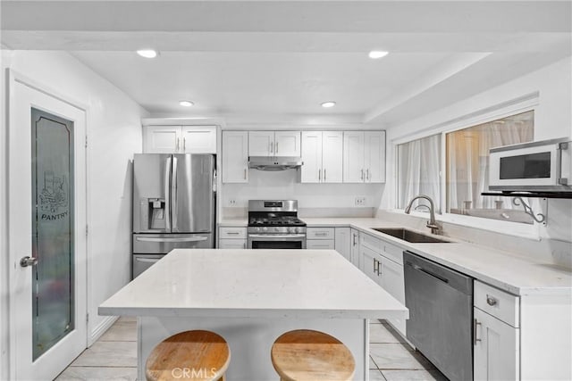 1558 Camelot Dr, Corona, CA 92882 - kitchen with stainless steel appliances, a sink, under cabinet range hood, white cabinets, and recessed lighting