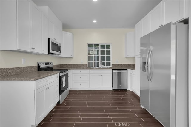 kitchen with appliances with stainless steel finishes, recessed lighting, white cabinets, and dark countertops