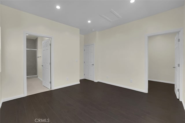 unfurnished bedroom with wood finished floors, attic access, baseboards, recessed lighting, and connected bathroom