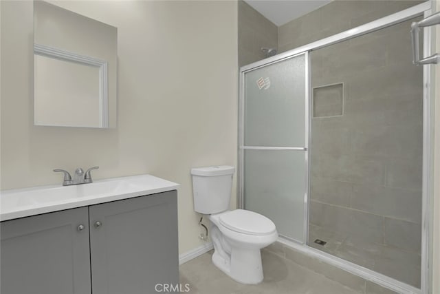 bathroom with tile patterned flooring, a shower stall, toilet, vanity, and baseboards