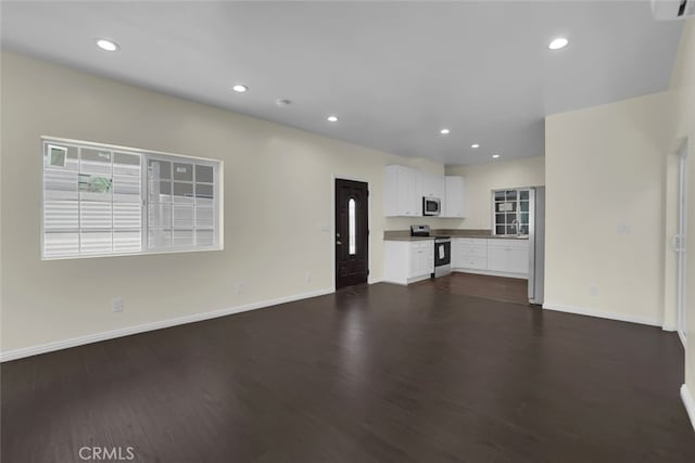unfurnished living room with dark wood-style flooring, recessed lighting, and baseboards