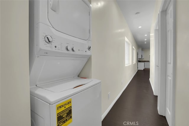 clothes washing area with stacked washer / dryer, baseboards, dark wood-style flooring, and recessed lighting