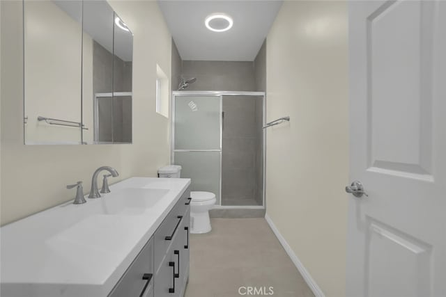 full bathroom featuring a shower stall, vanity, toilet, baseboards, and tile patterned floors