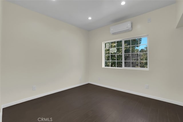 unfurnished room with an AC wall unit, dark wood finished floors, baseboards, and recessed lighting