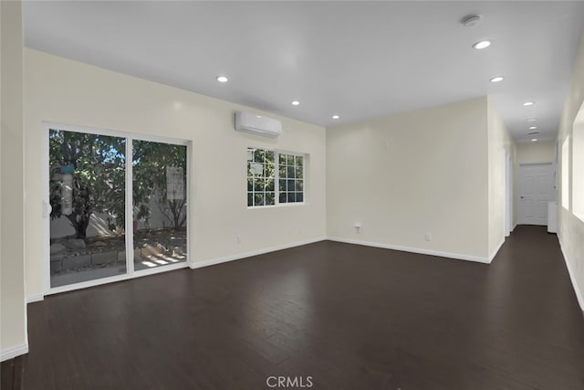 spare room with an AC wall unit, wood finished floors, recessed lighting, baseboards, and a smoke detector