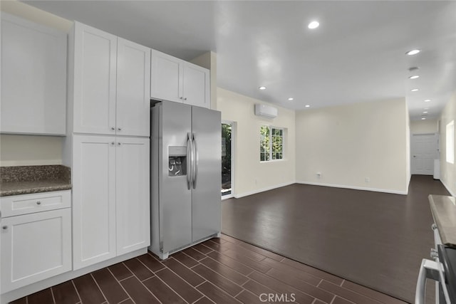 kitchen featuring stainless steel refrigerator with ice dispenser, an AC wall unit, white cabinetry, open floor plan, and dark wood-style floors